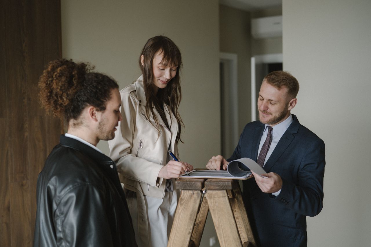 Crafting Captivating Headlines: Your awesome post title goes here A couple signing real estate documents with a realtor inside a new apartment.