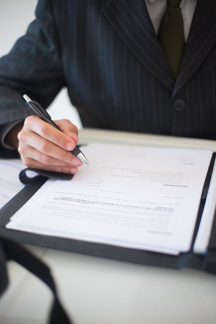 About Close-up of a business professional signing documents in an office setting.