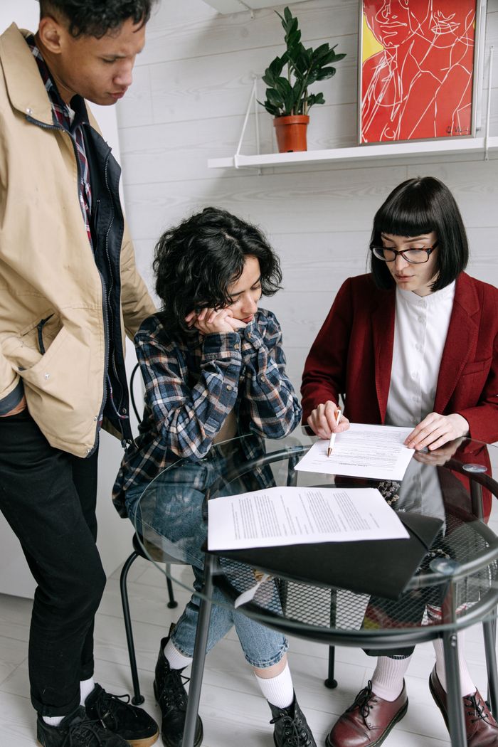 About Three individuals reviewing paperwork at a round table indoors.