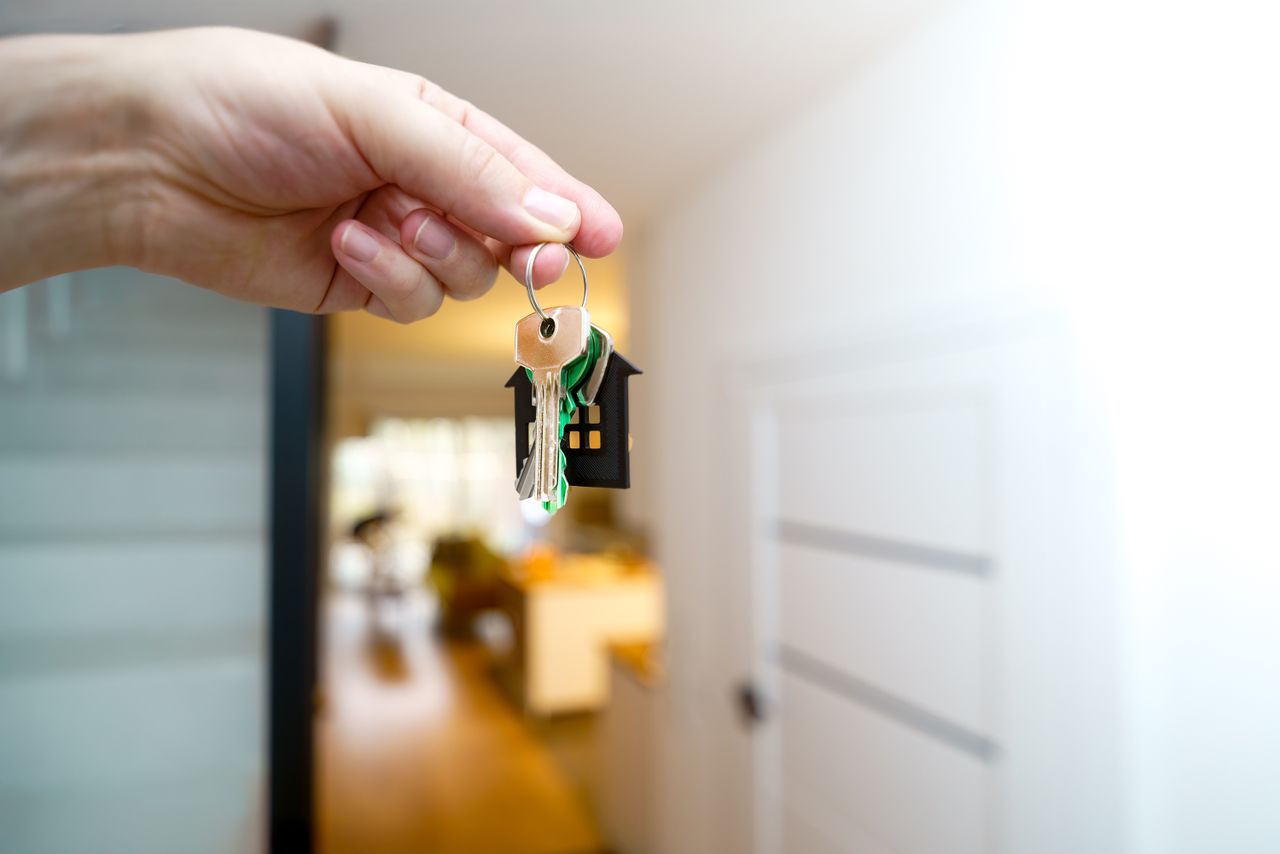 Mastering the First Impression: Your intriguing post title goes here A hand holding house keys inside a modern apartment, symbolizing new property ownership or rental.